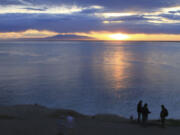 FILE - Visitors to Point Woronzof Park watch the sun set over Cook Inlet and Mount Susitna, on June 7, 2013, in Anchorage, Alaska. A federal judge on Tuesday, July 16, 2024, has suspended the lone lease stemming from a 2022 oil and gas lease sale in Alaska&rsquo;s Cook Inlet basin after finding problems with the environmental review the sale was based on.