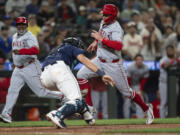 Los Angeles Angels&#039; Brandon Drury, right, runs past Seattle Mariners catcher Cal Raleigh, center, to score a run during the ninth inning of a baseball game Monday, July 22, 2024, in Seattle.
