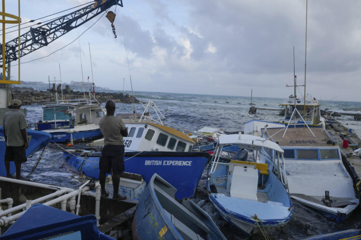 Fishermen look out at vessels damaged by Hurricane Beryl at the Bridgetown Fisheries in Barbados, Monday.