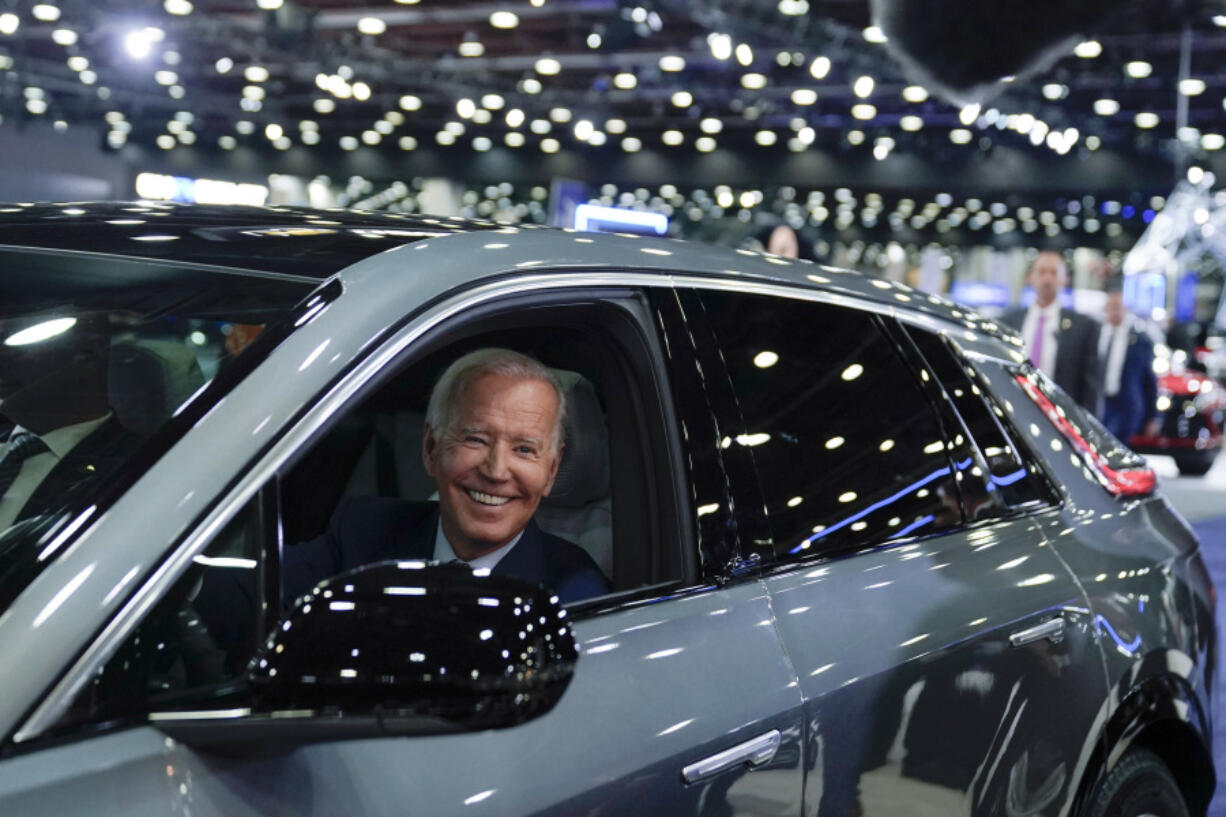 FILE - President Joe Biden drives a Cadillac Lyriq through the showroom during a tour at the Detroit Auto Show, Sept. 14, 2022, in Detroit. The Biden administration is awarding nearly $2 billion in grants to help restart or expand electric vehicle manufacturing and assembly sites in eight states, including the presidential battlegrounds of Michigan, Pennsylvania and Georgia. Grants totaling $1.7 billion will be issued by the Energy Department to create or retain thousands of union jobs and support auto-based communities that have long driven the U.S. economy, the White House said Thursday, July 11, 2024.