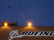 FILE - An airplane flies over a sign on Boeing&rsquo;s newly expanded 737 delivery center, Oct. 19, 2015, at Boeing Field in Seattle. The U.S. Justice Department plans to propose that Boeing plead guilty to fraud in connection with two deadly plane crashes involving its 737 Max jetliners, according to two people who heard federal prosecutors detail the offer Sunday, June 30, 2024. (AP Photo/Ted S.