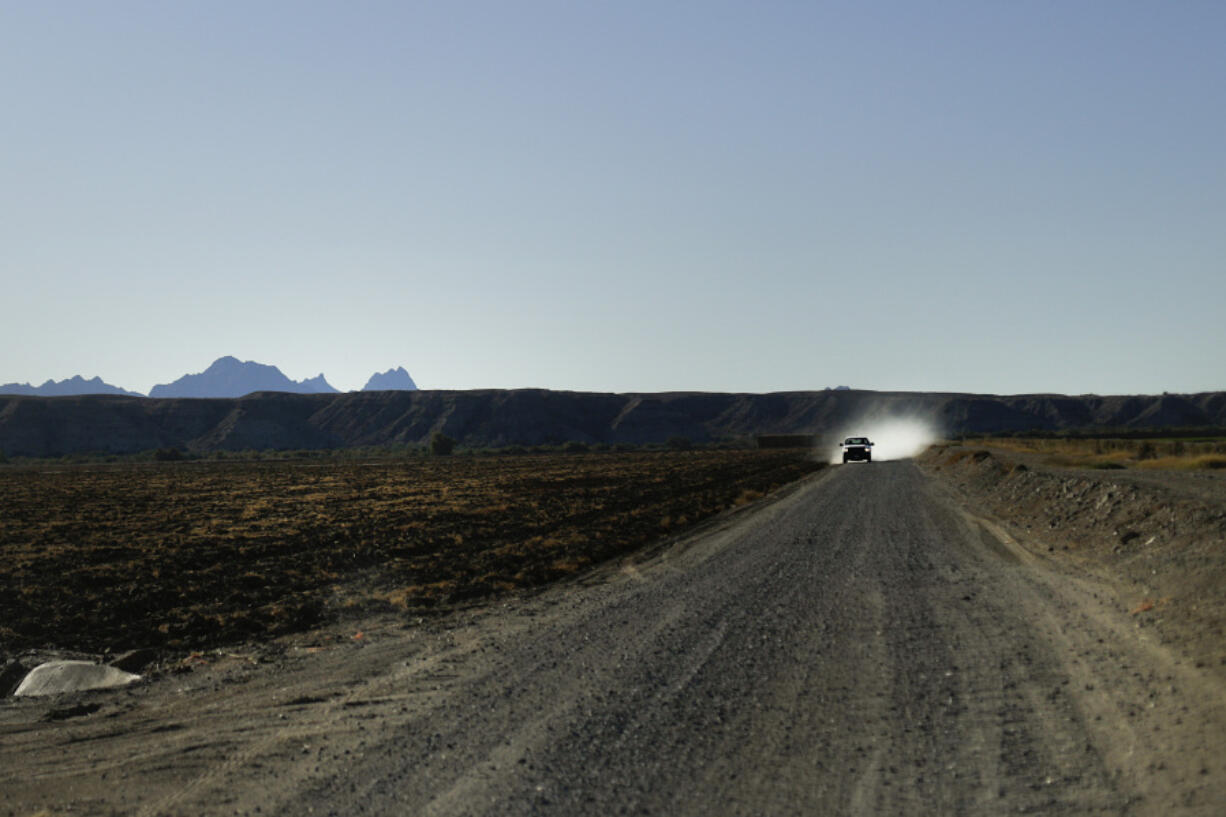 FILE - In this Friday, Nov. 13, 2015 photo, a pickup truck stirs up dust as it drives along the road between farmlands in Blythe, Calif. Under a new program, farmers of certain forage crops, including alfalfa, will be paid to shut off water to their fields for a short period of time during the hot summer months, which are not peak times for the crop and which won&rsquo;t affect its long-term viability. (AP Photo/Jae C.