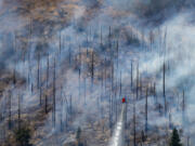 A helicopter drops water on the Park Fire near Butte Meadows, Calif., Tuesday, July 30, 2024.