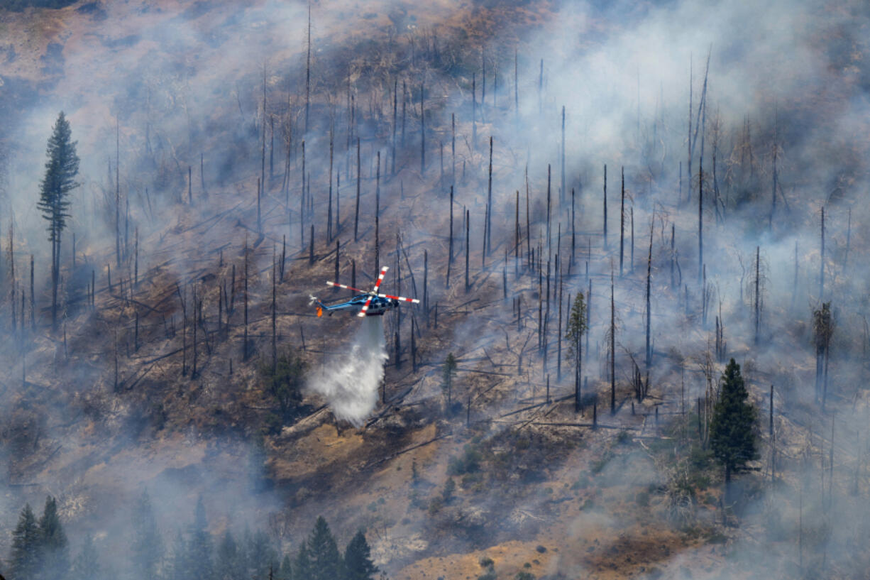 A helicopter drops water on the Park Fire near Butte Meadows, Calif., Tuesday, July 30, 2024.