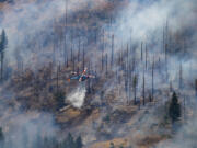 A helicopter drops water on the Park Fire near Butte Meadows, Calif., Tuesday, July 30, 2024.