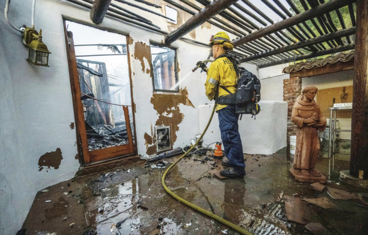 A firefighter hoses down hot spots at Noel Piri&rsquo;s home that was destroyed by the Hawarden Fire in Riverside, Calif., on Sunday, July 21, 2024.