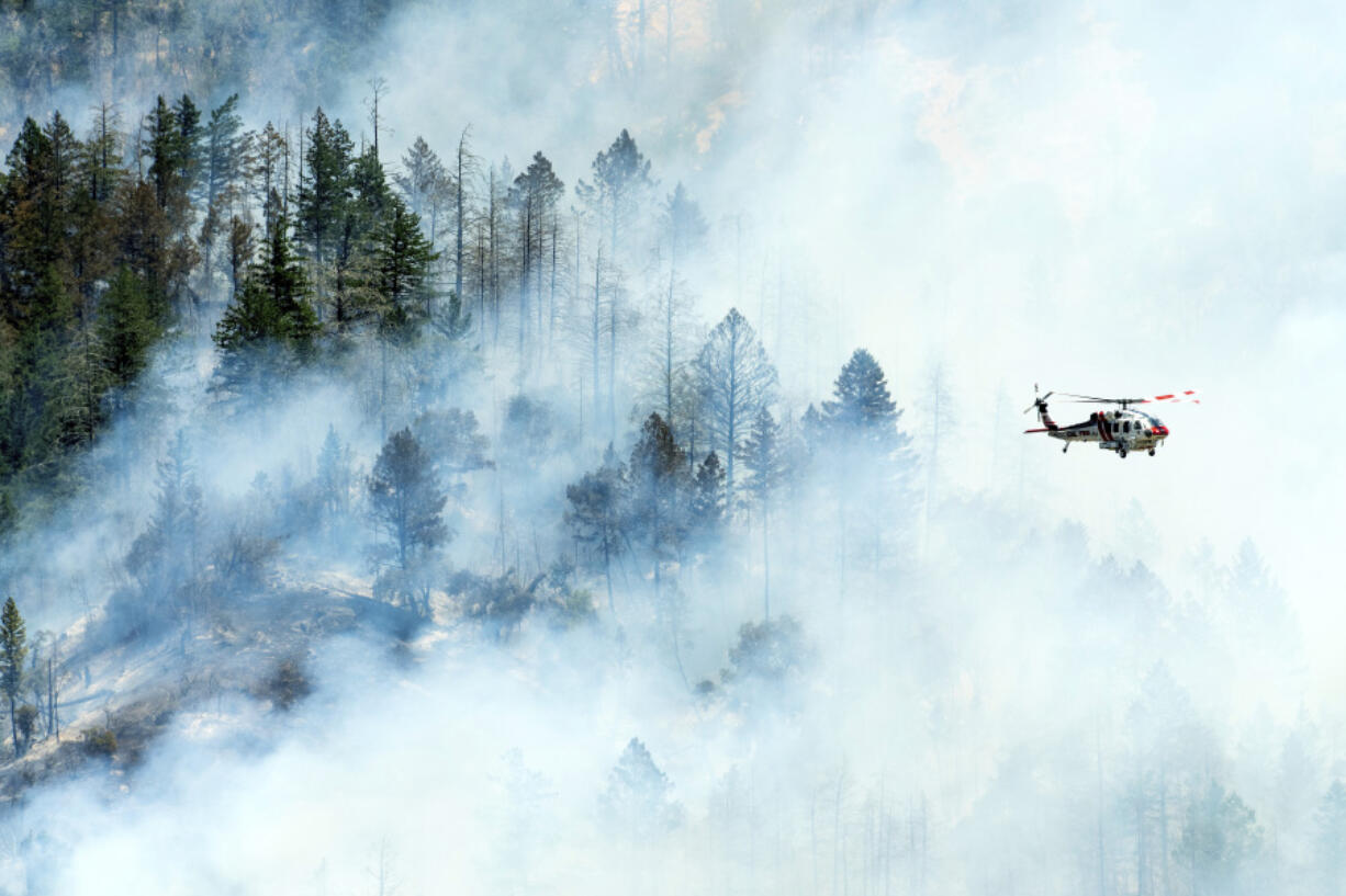 A helicopter flies above smoke as the Toll Fire burns near Calistoga, Calif., on Tuesday, July 2, 2024. An extended heat wave blanketing Northern California has resulted in red flag fire warnings and power shutoffs.