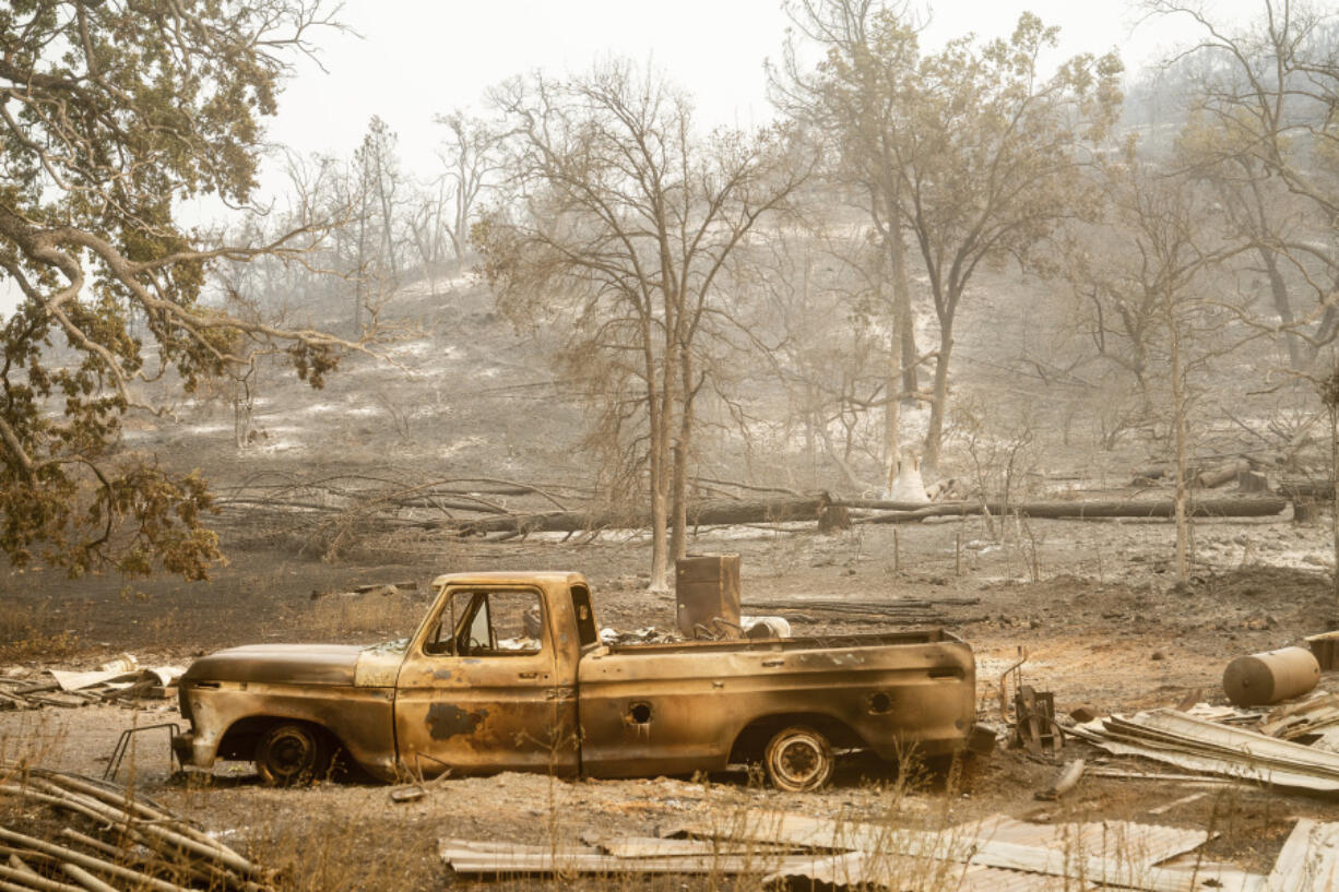 A charred vehicle rests below a hill in Paynes Creek after the Park Fire burned through the community in Tehama County, Calif., on Saturday, July 27, 2024.