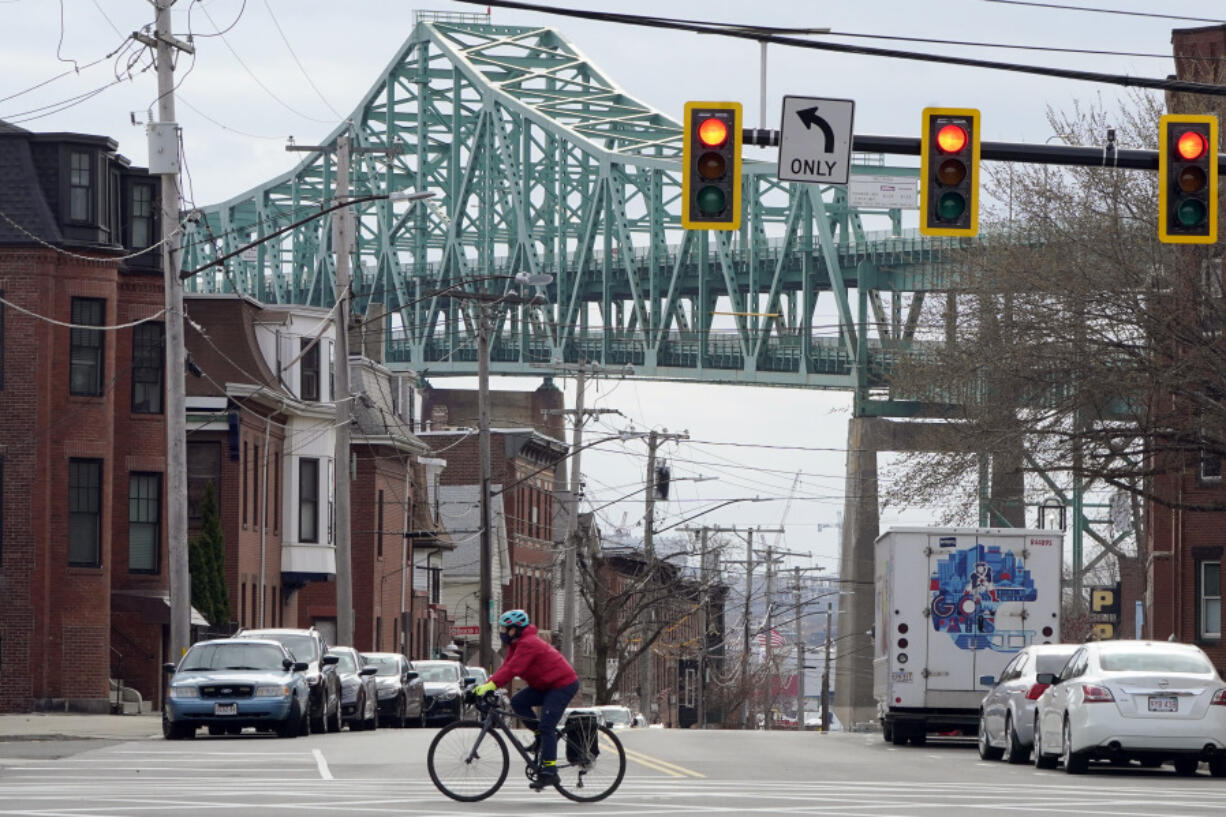 FILE - A cyclist rides along a street near the Tobin Memorial Bridge, background, in Chelsea, Mass., on Wednesday, March 31, 2021. After nearly 1,750 low-income people in the Boston suburb won a lottery to receive monthly stipends from the city from November 2020 to August 2021, researchers found that winners visited emergency departments significantly less than people who did not receive the monthly payments.