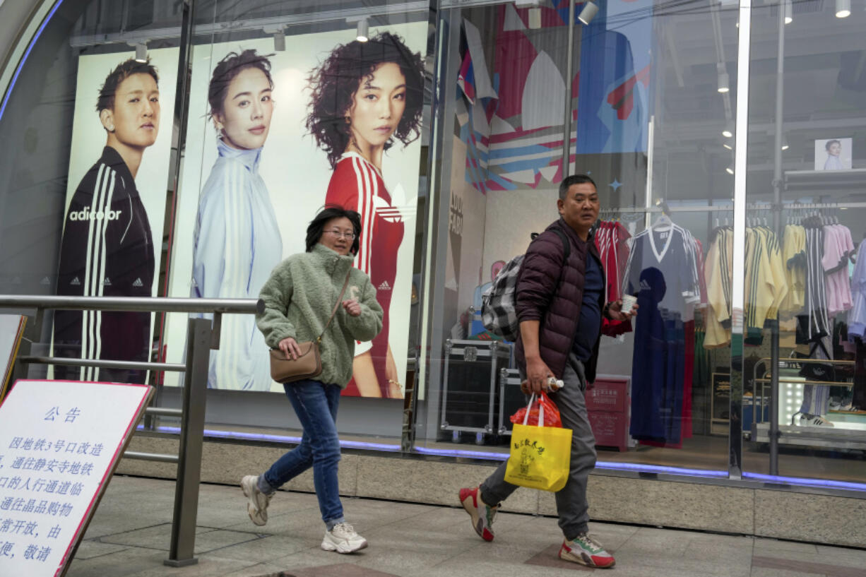 Shoppers walk by an apparel store in Shanghai on March 18.