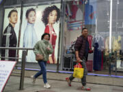 Shoppers walk by an apparel store in Shanghai on March 18.