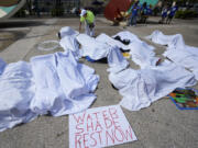 FILE - Demonstrators cover themselves with sheets to simulate workers killed by extreme heat, June 21, 2023, during a rally by outdoor workers demanding workplace protections against extreme heat, at the Stephen P. Clark Government Center in Miami.