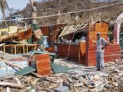 FILE - A man stands next to a business destroyed by Hurricane Beryl in Clifton, Union Island, St. Vincent and the Grenadines, July 4, 2024.