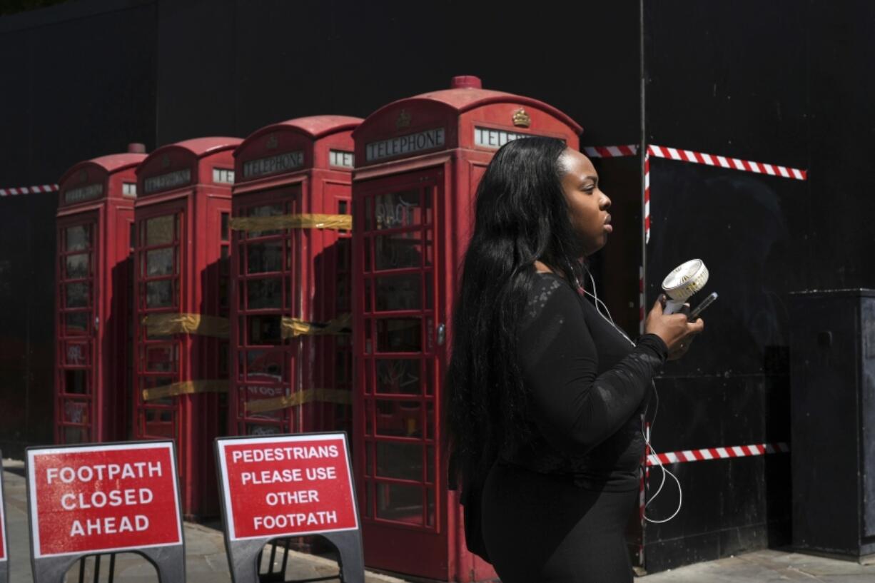 A woman cools herself with a fan June 26 during a hot day in London.