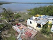 FILE - A woman retrieves belongings from her home that was hit by Hurricane Beryl in Portland Cottage, Clarendon, Jamaica, July 4, 2024.