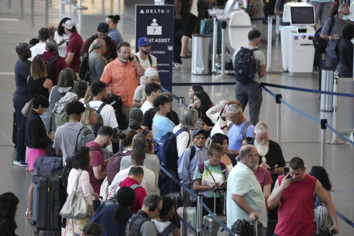 FILE - Passengers wait in line for assistance at the Delta Terminal, July 19, 2024, at Logan International Airport in Boston. Delta CEO Ed Bastian says the airline is facing $500 million in costs for the global technology breakdown that happened earlier this month.