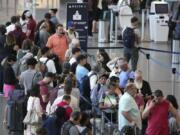 FILE - Passengers wait in line for assistance at the Delta Terminal, July 19, 2024, at Logan International Airport in Boston. Delta CEO Ed Bastian says the airline is facing $500 million in costs for the global technology breakdown that happened earlier this month.