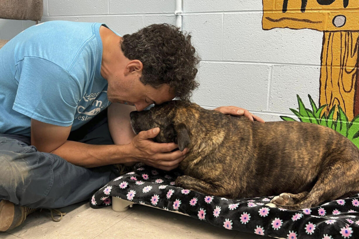 In this image provided by Skylar Sojka, shelter manager at Giles County, Va., Animal Shelter, Jesse Rochette embraces with Sparsy at the shelter in Pearisburg, Va. A group of cavers, including Rochette, who were exploring in western Virginia over the weekend rescued the dog that the Giles County shelter is calling a &ldquo;living miracle&rdquo; after she was found 40 to 50 feet down in a cave.