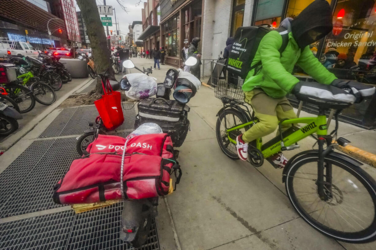 FILE - A food delivery worker rides down a sidewalk after a pickup from a restaurant in New York on Jan. 29, 2024. DoorDash is stepping up efforts to stop delivery drivers who are breaking traffic laws.