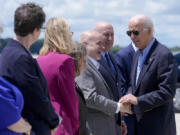 President Joe Biden, right, shakes hands with Rep. Mark Pocan, D-Wis., as former Wisconsin Gov. Jim Doyle, second from right, looks on, upon arriving at Dane County Regional Airport to attend a campaign rally in Madison, Wis., Friday, July 5, 2024.