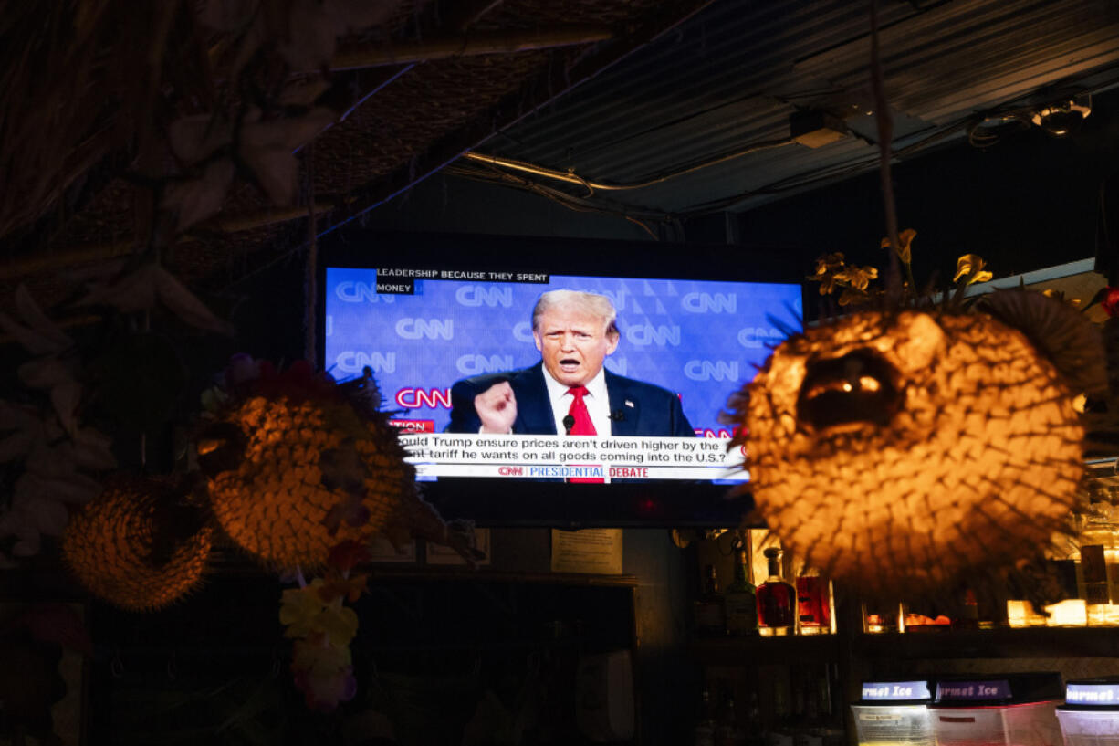 Republican presidential candidate former President Donald Trump is seen on a television near puffer fish lamps as people watch the presidential debate at Hula Hula, a tiki themed karaoke bar, Thursday, June 27, 2024, in Seattle.