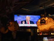 Republican presidential candidate former President Donald Trump is seen on a television near puffer fish lamps as people watch the presidential debate at Hula Hula, a tiki themed karaoke bar, Thursday, June 27, 2024, in Seattle.