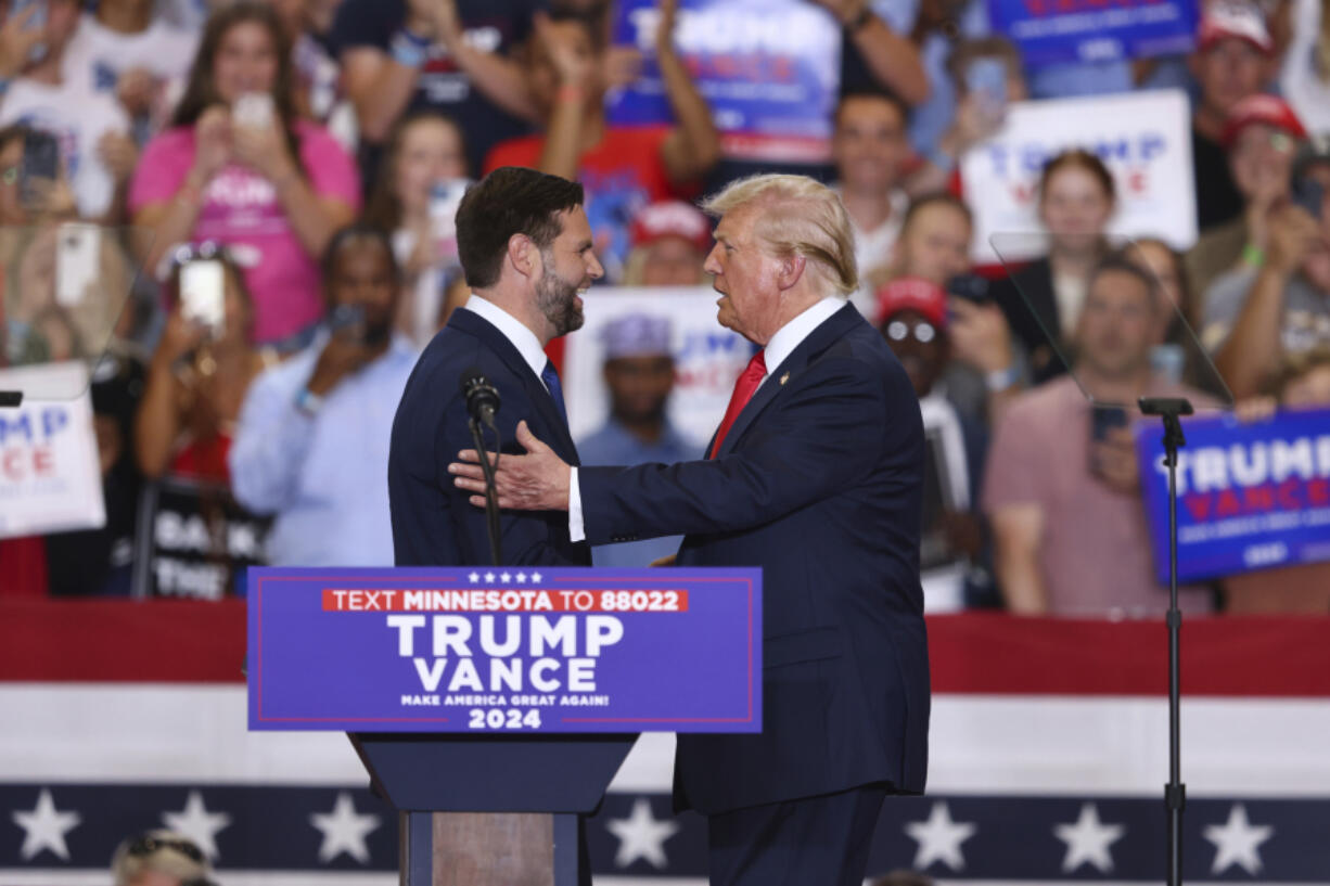 Republican presidential candidate former President Donald Trump and Republican vice presidential candidate Sen. JD Vance, R-Ohio,  greet each other at a campaign rally, Saturday, July 27, 2024, in St. Cloud, Minn.