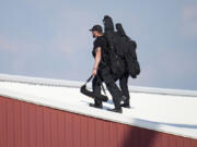 Police snipers walk on a roof to set up before Republican presidential candidate former President Donald Trump speaks at a campaign event in Butler, Pa., on Saturday, July 13, 2023. (AP Photo/Gene J.