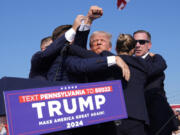 Republican presidential candidate former President Donald Trump gestures as he is surrounded by U.S. Secret Service agents at a campaign rally, Saturday, July 13, 2024, in Butler, Pa.