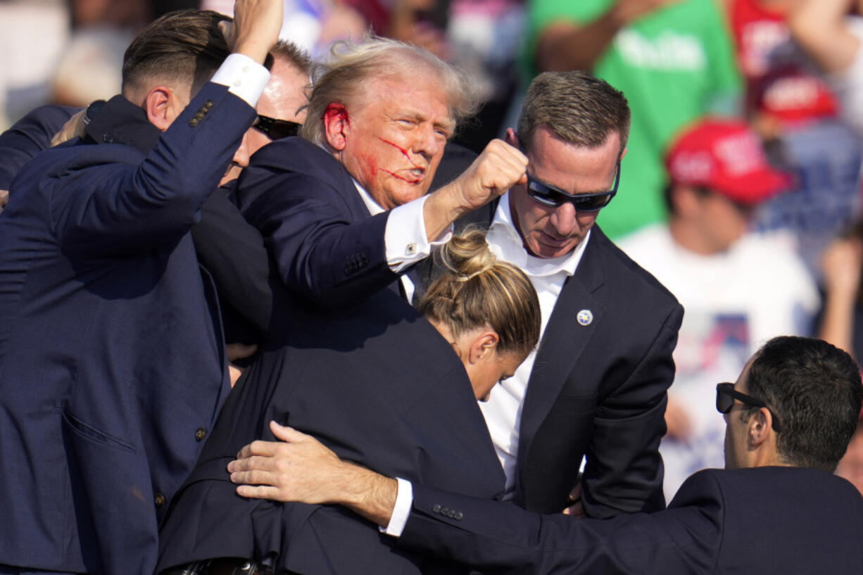 Republican presidential candidate former President Donald Trump is helped off the stage by U.S. Secret Service at a campaign event in Butler, Pa., on Saturday, July 13, 2024. (AP Photo/Gene J.