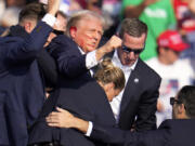 Republican presidential candidate former President Donald Trump is helped off the stage by U.S. Secret Service at a campaign event in Butler, Pa., on Saturday, July 13, 2024. (AP Photo/Gene J.