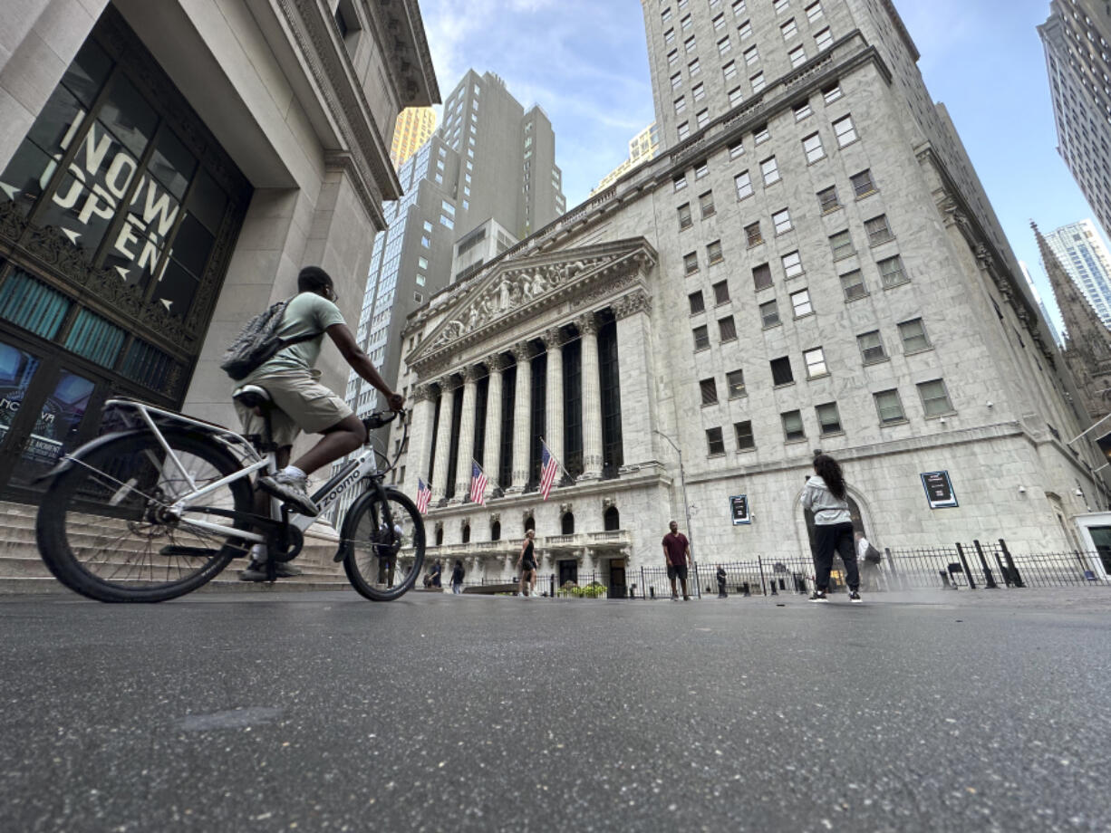 A bike rider approaches the New York Stock Exchange, rear, on Tuesday, July 9, 2024, in New York. Global shares are mostly higher, with Japan&rsquo;s benchmark Nikkei 225 jumping 2% to finish at another record high.