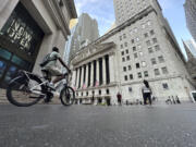 A bike rider approaches the New York Stock Exchange, rear, on Tuesday, July 9, 2024, in New York. Global shares are mostly higher, with Japan&rsquo;s benchmark Nikkei 225 jumping 2% to finish at another record high.