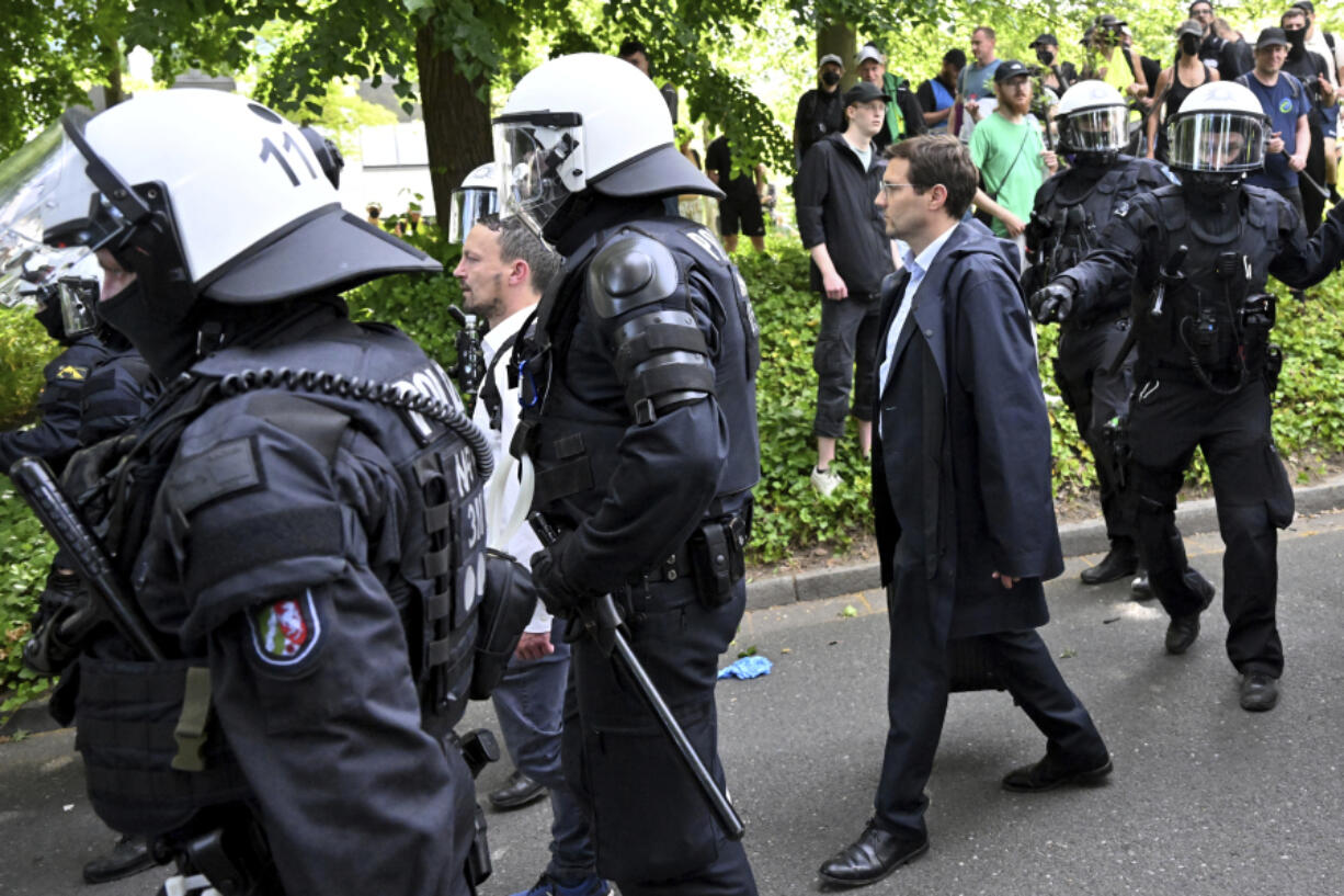 Participants of the AfD party conference are escorted by police past demonstrators in Essen, Germany, Saturday June 29, 2024. The far-right Alternative for Germany party is holding a convention in the western city of Essen and large-scale protests against the party are taking place.