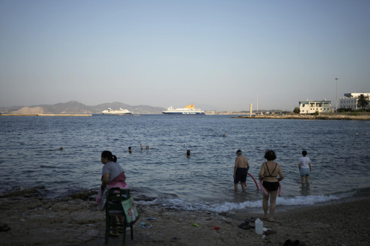 People swim on a small beach, during a warm morning at Athens&rsquo; port city of Piraeus, Monday, July 22, 2024. The heatwave continues in Greece, with temperatures hovering at 40 degrees Celsius (104 Fahrenheit) in several places, but the meteorologists expecting to slight drop from tomorrow.