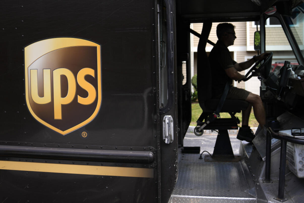 FILE - A United Parcel Service driver steers through a neighborhood while delivering packages, June 30, 2023, in Haverhill, Mass. As areas across the U.S. continue to experience extreme heat, employers have taken steps to protect workers from high temperatures. UPS has added more cooling equipment to its vehicles and facilities.