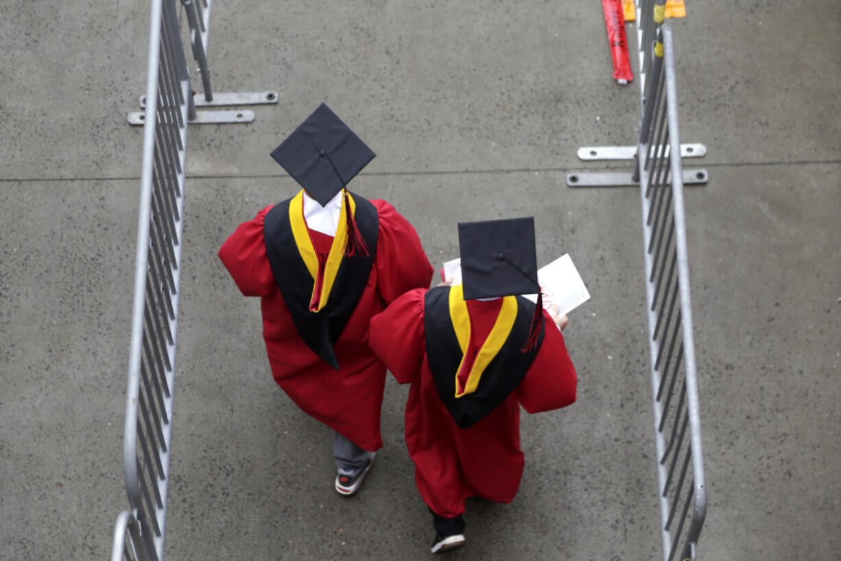 FILE - In this May 13, 2018, file photo, new graduates walk into the High Point Solutions Stadium before the start of the Rutgers University graduation ceremony in Piscataway Township, N.J.  Americans are increasingly skeptical about the value and cost of college, with most saying they feel the U.S. higher education system is headed in the &ldquo;wrong direction,&rdquo; according to a new poll.