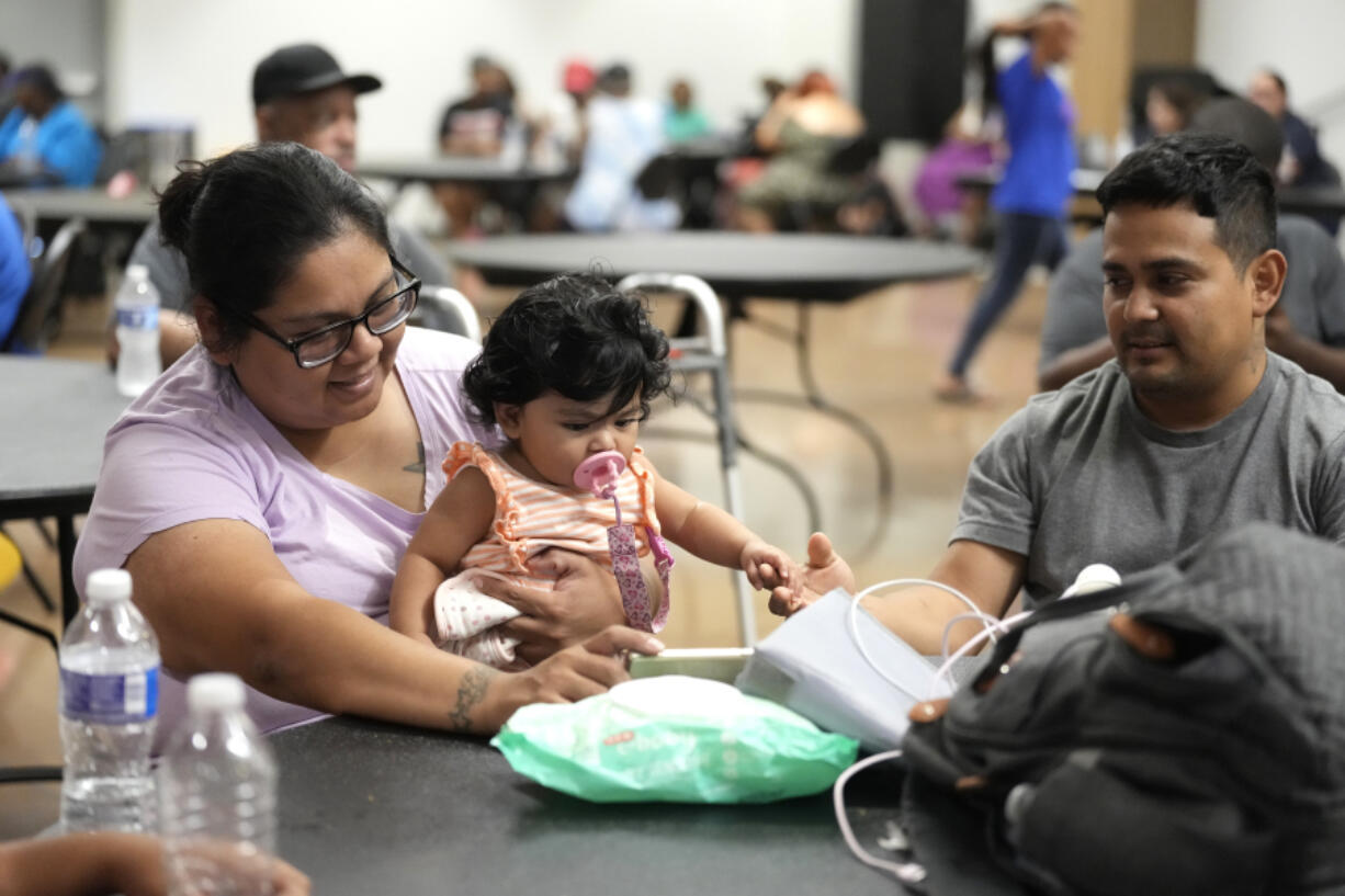 FILE - Keyla Herrera entertains her eight-month-old daughter, Emma, with a movie on her cell phone next to her husband, Edgar, as they sat inside of the cooling center set up inside of Sunnyside Health and Multi-Service Center on Wednesday, July 10, 2024. As of Thursday, July 18, most Houston residents finally had electricity after more than a week of widespread outages.