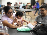 FILE - Keyla Herrera entertains her eight-month-old daughter, Emma, with a movie on her cell phone next to her husband, Edgar, as they sat inside of the cooling center set up inside of Sunnyside Health and Multi-Service Center on Wednesday, July 10, 2024. As of Thursday, July 18, most Houston residents finally had electricity after more than a week of widespread outages.