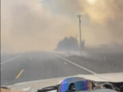 A motorist drives past the Gwen Fire on Highway 3 outside of Juliaetta, Idaho, on Thursday.