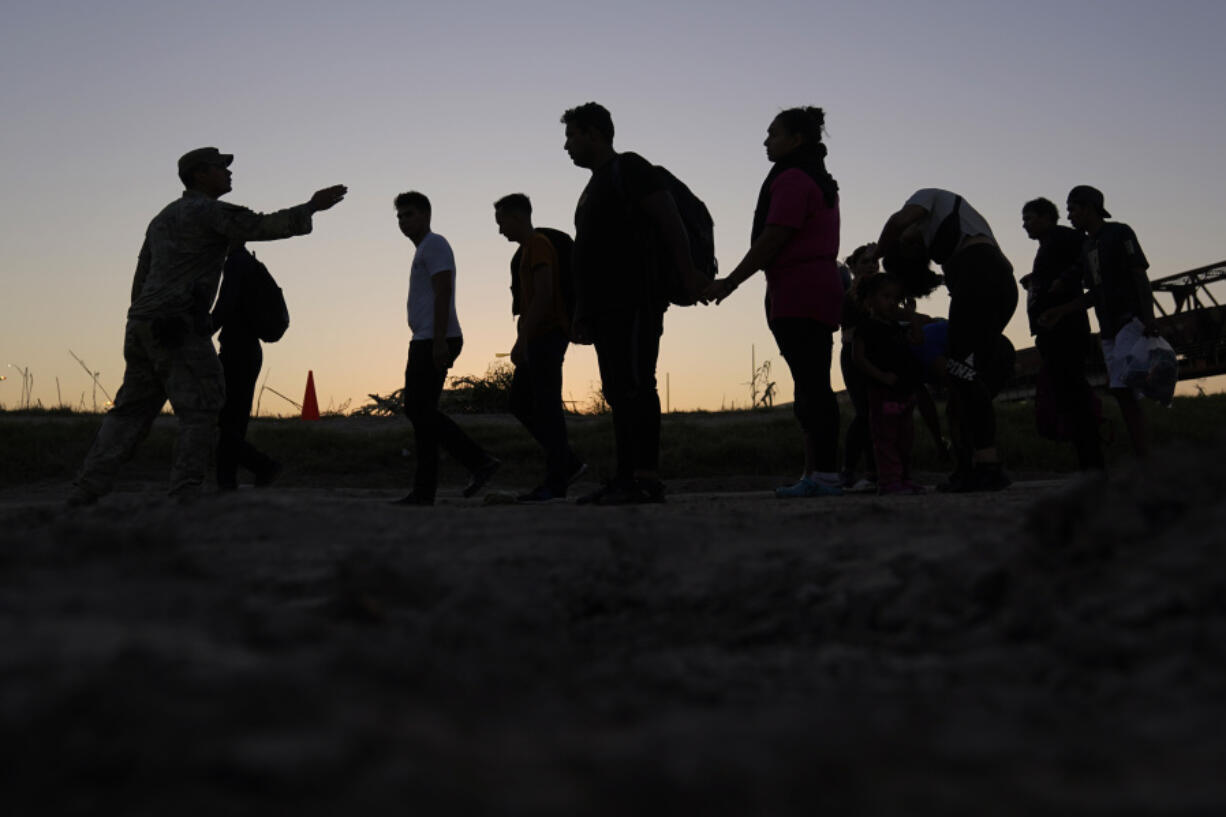 FILE - Migrants who crossed the Rio Grande and entered the U.S. from Mexico are lined up for processing by U.S. Customs and Border Protection, Sept. 23, 2023, in Eagle Pass, Texas.  U.S. authorities say border arrests during July have plummeted to a new low for Joe Biden&rsquo;s presidency, raising prospects that a temporary ban on asylum may be lifted soon. The Border Patrol is expected to arrest migrants about 57,000 times during the month, down about 30% from June and the lowest tally since September 2020, when COVID-19 slowed movement across many borders.