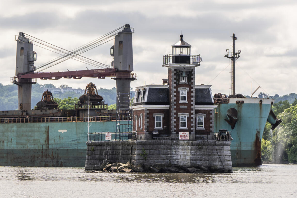 A ship passes the Hudson Athens Lighthouse, Wednesday, June 12, 2024, in Hudson, N.Y.  The 150-year-old lighthouse is in danger of toppling into the water, and advocates for the  lighthouse in the middle of Hudson River are urgently trying to save it.