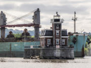 A ship passes the Hudson Athens Lighthouse, Wednesday, June 12, 2024, in Hudson, N.Y.  The 150-year-old lighthouse is in danger of toppling into the water, and advocates for the  lighthouse in the middle of Hudson River are urgently trying to save it.
