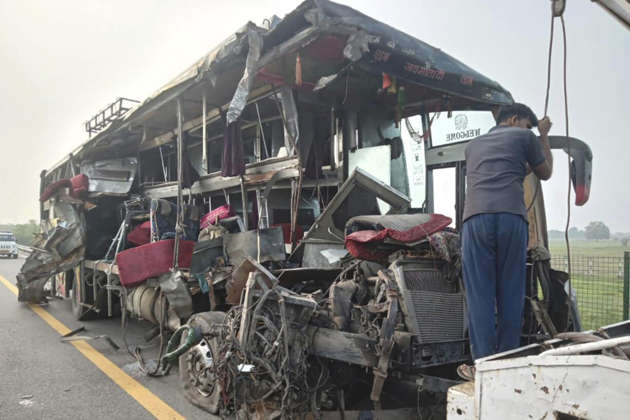 A roadside assistance worker tows away the mangled remains of a double-decker passenger bus that collided with a milk truck, near Unnao, in northern India state of Uttar Pradesh, Wednesday, July 10, 2024. Officials said the collision killed and injured multiple people.