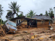 A damaged car and a house after landslides hit hilly villages in Wayanad district, Kerala state, India, Tuesday, July 30, 2024.