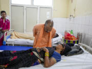 Uttar Pradesh State Chief Minister Yogi Adityanath, talks to a woman who was injured in a stampede as she receives treatment at Hathras district hospital, Uttar Pradesh, India, Wednesday, July 3, 2024. Thousands of people at a religious gathering rushed to leave a makeshift tent, setting off a stampede Tuesday that killed more than hundred people and injured scores.