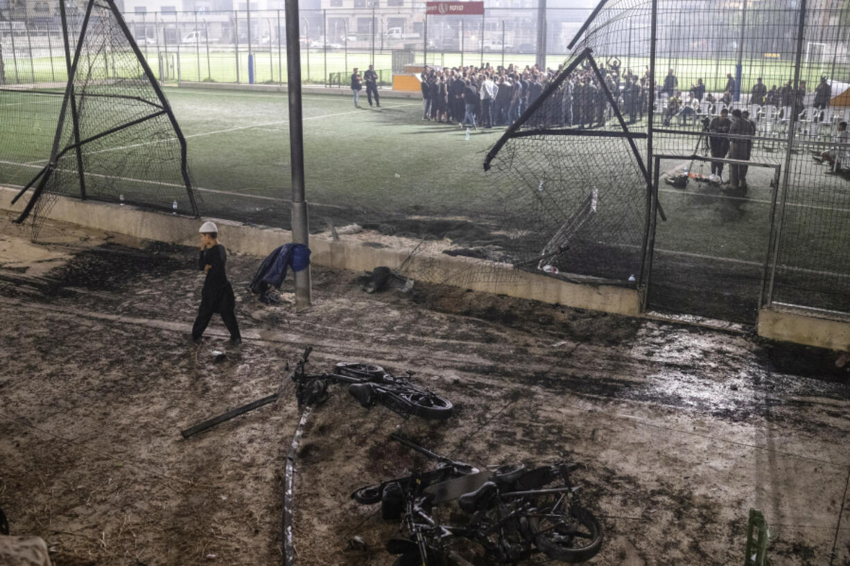 FILE - A boy walks past bicycles left next to a soccer pitch that was hit by a rocket, killing 12 children and teenagers, in the Druze town of Majdal Shams, in the Israeli-annexed Golan Heights, Saturday, July 27, 2024. Two days after the attack questions remain about why it happened and who is responsible.