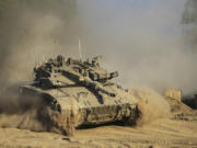 An Israeli soldier moves on the top of a tank near the Israeli-Gaza border, as seen from southern Israel, Sunday, July 14, 2024.