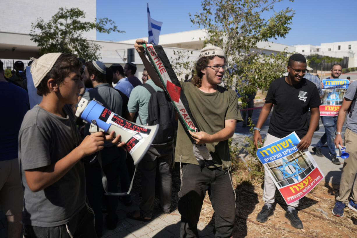 Right-wing Israelis, one holding a Palestinian scarf, at a protest outside of the initial hearing in military court for nine Israeli soldiers over what a defense lawyer said were allegations of sexual abuse of a Palestinian at a shadowy facility where Israel has held prisoners from Gaza during the war, in Beit Lid military base, Tuesday, July 30, 2024.