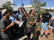 Right-wing Israelis, one holding a Palestinian scarf, at a protest outside of the initial hearing in military court for nine Israeli soldiers over what a defense lawyer said were allegations of sexual abuse of a Palestinian at a shadowy facility where Israel has held prisoners from Gaza during the war, in Beit Lid military base, Tuesday, July 30, 2024.